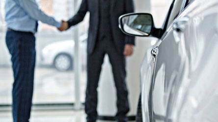 Vendedor de coches dándose la mano con el cliente