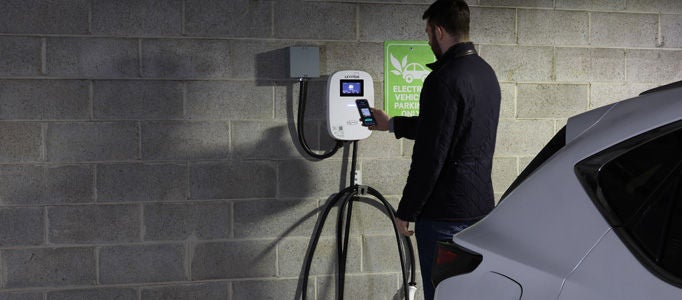 Hombre cargando un vehículo eléctrico en un estacionamiento